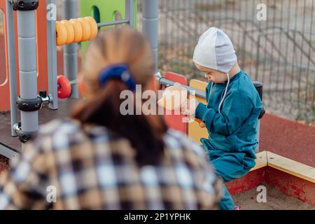 Ein Junge mit Down-Syndrom geht mit seiner Mutter im Park spazieren Stockfoto