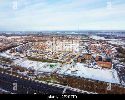 Luftdrohne. Ebbsfleet Garden City in Kent, im Dezember 2022 von Schnee bedeckt. Neubauten und gefrorener See entlang der Autobahn A2. Stockfoto