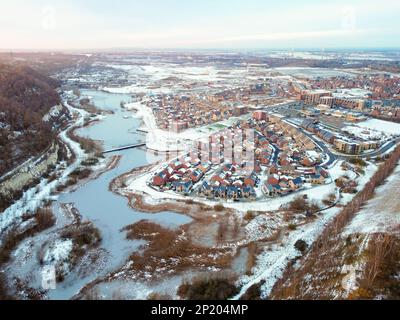 Luftdrohne. Ebbsfleet Garden City in Kent, im Dezember 2022 von Schnee bedeckt. Neubauten und gefrorener See entlang der Autobahn A2. Stockfoto