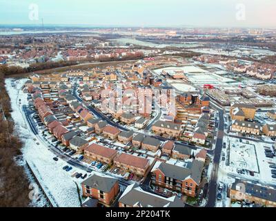 Luftdrohne. Ebbsfleet Garden City in Kent, im Dezember 2022 von Schnee bedeckt. Neubauten und gefrorener See entlang der Autobahn A2. Stockfoto