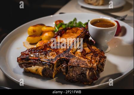 Rindfleisch mit Kartoffeln. Ein Stück T-Bone-Steak auf dem Teller mit Sauce. Lecker und lecker. Stockfoto