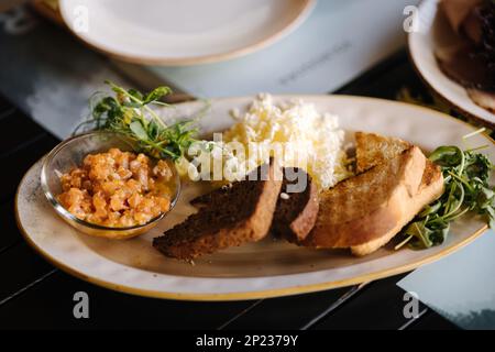 Lachstartar serviert mit geriebener Butter und geröstetem Brot. Tisch mit Essen auf der Terrasse Stockfoto
