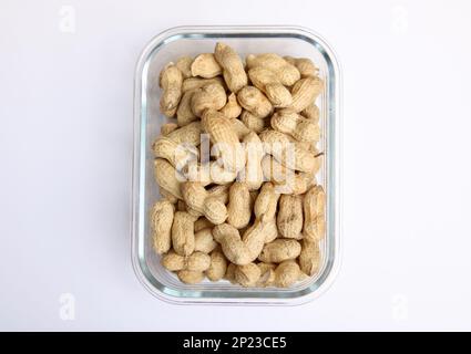 Glasschale mit Erdnüssen oder Affennüssen auf weißem Hintergrund Stockfoto