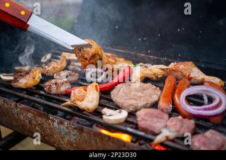 Köstliches Fleisch mit Gemüse auf Holzkohlegrill. Ruh dich aus, Barbecue. Stockfoto