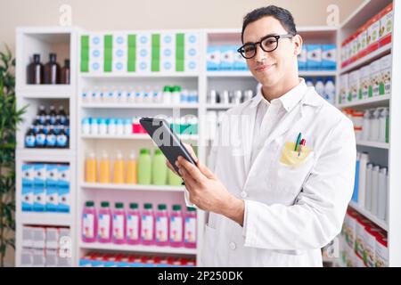 Junger hispanic-Mann Apotheker mit Touchpad in der Apotheke arbeiten Stockfoto