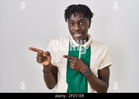 Ein afrikanischer Mann mit Dreadlocks, der über einem isolierten Hintergrund steht und zur Seite zeigt, besorgt und nervös mit beiden Händen, besorgt und überraschter Ausdruck Stockfoto