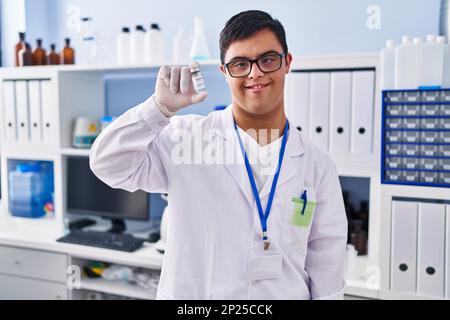 Mann mit Down-Syndrom, der im Labor eine Wissenschaftleruniform trägt und die Dosis des Covid-19-Impfstoffs hält Stockfoto