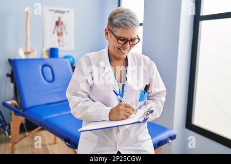 Frau im mittleren Alter, Physiotherapeutin, die in der Reha-Klinik auf die Zwischenablage schreibt Stockfoto