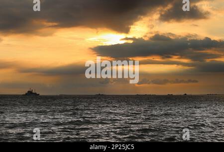 Bewölkter Sonnenuntergang mit Schiffen vor Anker in Manila Bay, Philippinen Stockfoto