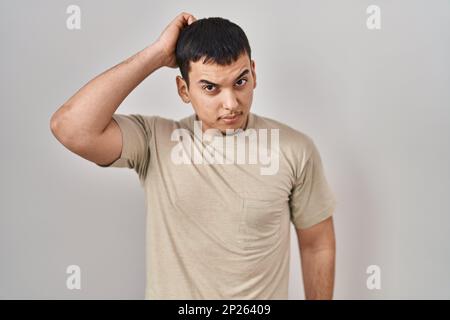 Ein junger arabischer Mann, der ein legeres T-Shirt trägt, verwirrt und fragt sich nach Fragen. Unsicher mit Zweifeln, mit Hand an Kopf denken. Nachdenkliches Konzept. Stockfoto