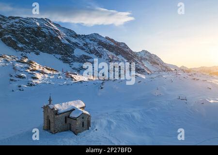 Sonnenuntergang am Alpe Prabello mit Santuario Madonna della Pace im Winter. Lanzada, Valmalenco, Valtellina, Sondrio District, Lombardei, Italien, Europa. Stockfoto