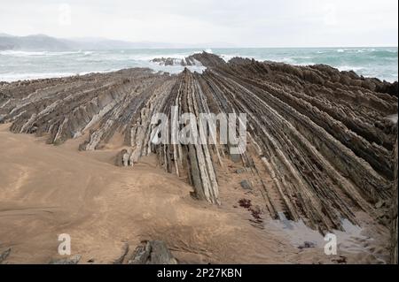 Blick auf steil geneigte Schichten von Flysch-geologischer Formation an der Atlantikküste bei Zumaia bei Ebbe, Baskenland, Spanien Stockfoto
