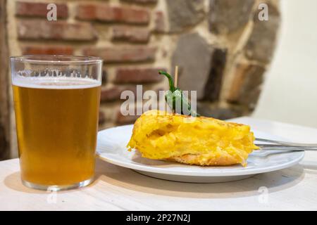 Typischer Mini-Burger-Snack aus dem Baskenland, Pinchos oder Pinxtos, ein kleines Stück Brot mit Omelette und verschiedenen Belägen, serviert in der Bar mit gla Stockfoto