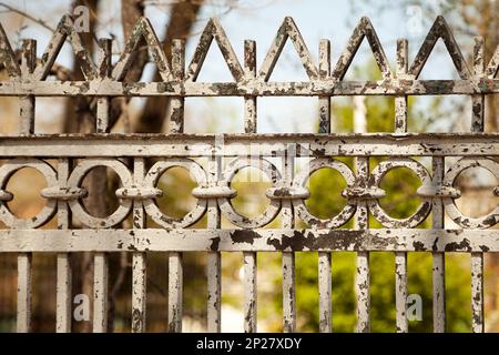 Alte geschälten Metall Zaun in einem Garten. Bunten Hintergrund mit geometrischen Muster ornament Stockfoto