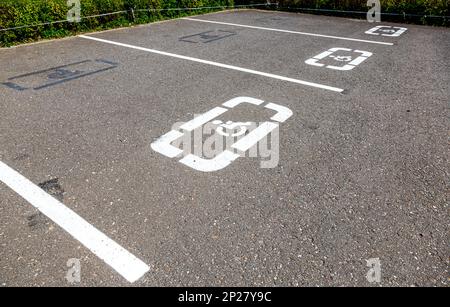 Parkplätze mit Hinweisschildern für Behinderte und Markierungslinien auf Asphalt an der Stadtstraße Stockfoto
