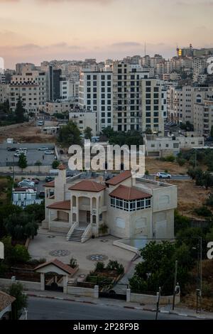 Stadtbild von Ramallah bei Sonnenaufgang, hohe Gebäude und Bäume mit Blick auf die Sonne Stockfoto