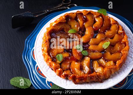 Speisekonzept hausgemachte Tarte Tatin Upside-down-Apfelkuchen auf schwarzem Schieferstein mit Kopierbereich Stockfoto