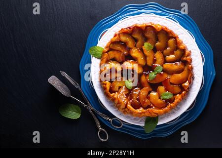 Speisekonzept hausgemachte Tarte Tatin Upside-down-Apfelkuchen auf schwarzem Schieferstein mit Kopierbereich Stockfoto