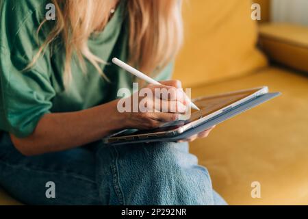 Nahaufnahme einer unbekannten Frau, die mit einem Eingabestift in einer App auf einem Tablet malt. Stockfoto