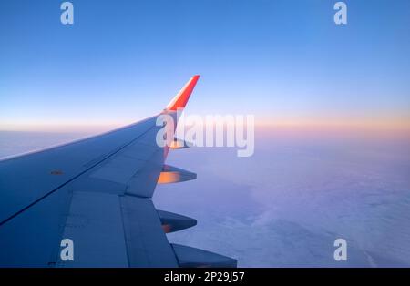 Flugzeug fliegt in den Himmel, Blick auf thу Flugzeugflügel durch ein Fenster Stockfoto