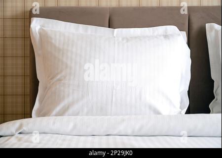 Nahaufnahme weißer Kissen auf einem Bett im Hotel, weißes, sauberes Kissen in einem komfortablen Zimmer, Blick nach vorne Stockfoto