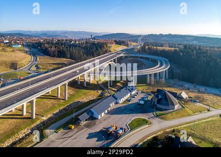 Neue Autobahn in Polen auf der Nationalstraße Nr. 7, E77, genannt Zakopianka. Überführung mit einem Kreisverkehr, Viadukten, Zufahrtsstraßen und Autos. Skomieln Stockfoto