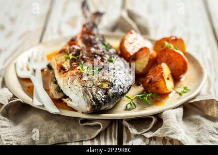 Hausgemachte geröstete Kartoffeln und Seebrassen mit Kirschtomaten und Thymian Stockfoto