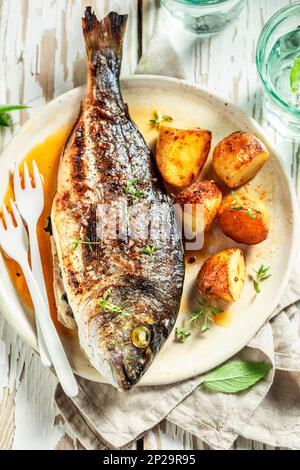 Meerbrasse geröstet mit Kartoffeln, Kirschtomaten und Thymian im Sommer Stockfoto