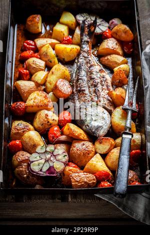 Geröstete Meerbrasse mit Kartoffeln, Kräutern und Tomaten im Sommer Stockfoto