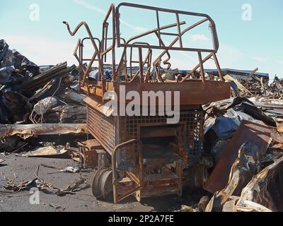 Ein verbrannter mobiler Aufzug zwischen einem Haufen von Bauschutt und verrostetem Metall. Bleibt nach dem Feuer. Stockfoto