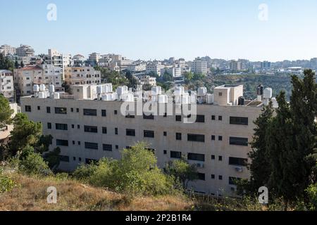 Ramallah, Ramallah und al-Bireh Governorate, Palästina, 28. Juli 2022: Arab Town with Old White Stone Buildings on Hills with Water Tanks on Top and TR Stockfoto