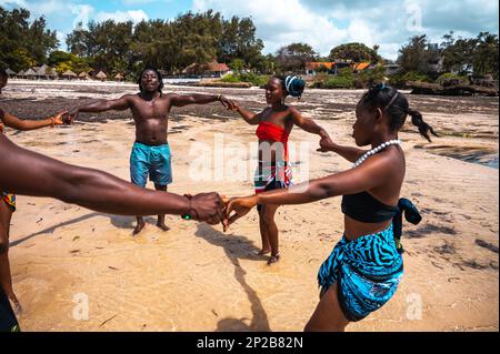 Kenianer tanzen am Strand mit typischen einheimischen Kleidern Stockfoto