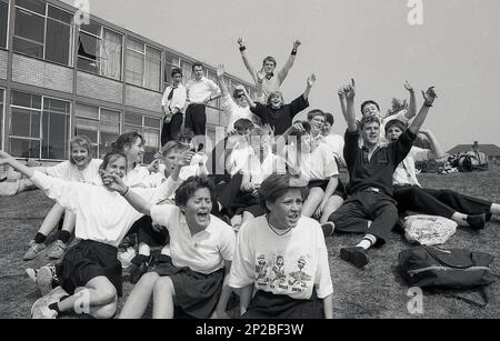 1989, Sporttag der Sekundarschule, männliche und weibliche Schüler im Teenageralter, die draußen sitzen und Spaß haben, während sie ihre Mitbewerber anfeuern, England, Großbritannien Stockfoto