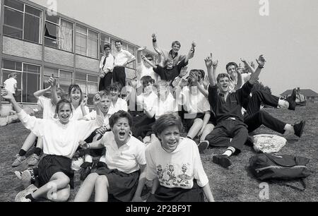 1989, Sporttag der Sekundarschule, männliche und weibliche Schüler im Teenageralter, die draußen sitzen und Spaß haben, während sie ihre Mitbewerber anfeuern, England, Großbritannien Stockfoto