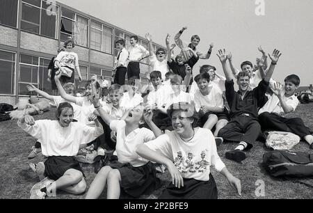 1989, Sporttag der Sekundarschule, männliche und weibliche Schüler im Teenageralter, die draußen sitzen und Spaß haben, während sie ihre Mitbewerber anfeuern, England, Großbritannien Stockfoto