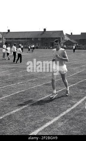 1989, Sporttag an einer Sekundarschule, ein Teenager in Führung bei einem Laufrennen auf einer Grasstrecke, Sleaford, Lincs, England, Großbritannien. Stockfoto