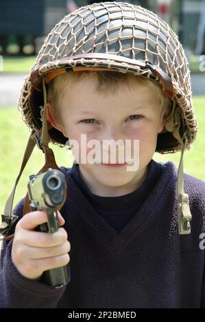8-jähriger Junge, der Soldaten spielt und eine Spielzeugwaffe schleicht. Stockfoto
