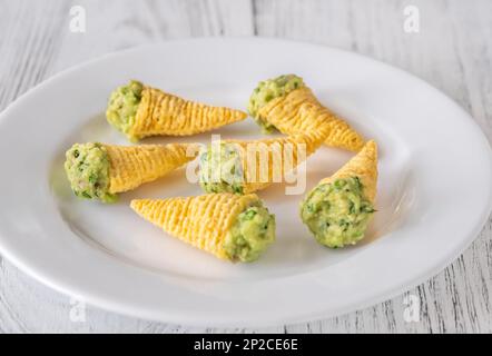 Tortilla-Chips, gefüllt mit Guacamole auf dem Teller Stockfoto