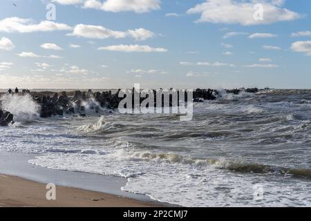 Wellen, die gegen das Wellenbrecherwasser stürzen, das aus Graubeton-Tetrapoden besteht. Liepaja, Lettland. Liepājas Ziemeļu mols Stockfoto