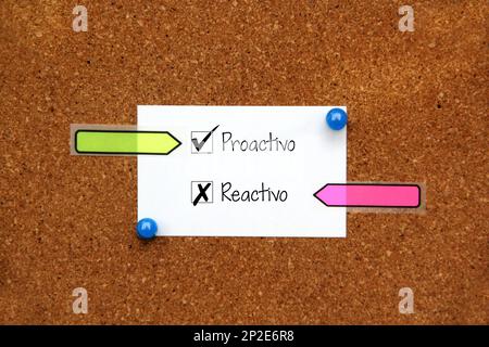 Weiße und mehrfarbige Hinweise auf Korktafel mit Meldung in spanischer Sprache „proaktiv reaktiv“ Stockfoto