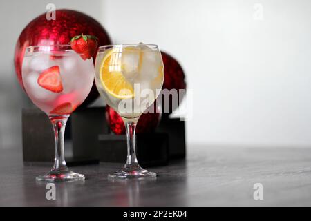 Erdbeer und Orangengin auf altem grauen Tisch mit roten Kugeln Stockfoto