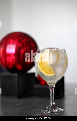 Orange Gin auf altem grauen Tisch mit roten Kugeln Stockfoto