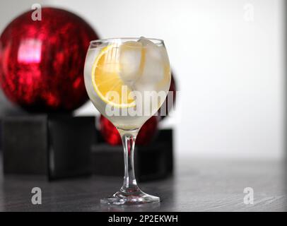 Orange Gin auf altem grauen Tisch mit roten Kugeln Stockfoto