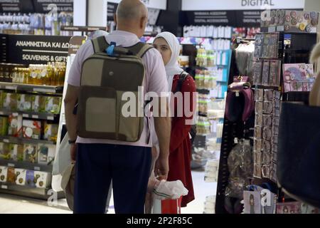 Athen Griechenland Internationaler Flughafen Athen (AIA) Eleftherios Venizelos Frau trägt Hijab und spricht mit dem Mann im Geschäft Stockfoto