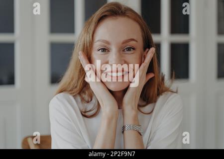 Oh, mein gott! Aufgeregt überrascht lächelnde Frau berührt Wangen, die mit dem Verkaufsvorschlag zufrieden sind. Das erstaunt berührte Mädchen kann nicht an Glück glauben unerwarteter Glibber Stockfoto