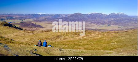 Zwei Wanderinnen, die sich auf dem Gipfel von Ben Vorlich in der Nähe von Pitlochry, Schottland, entspannen und die weitläufige Aussicht genießen Stockfoto