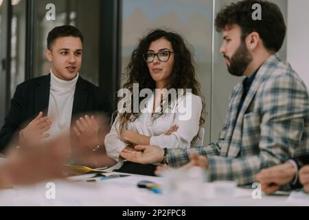 Junge Kollegen, die am Arbeitsplatz über Marketing sprechen. Ein gutaussehender Mann, der Ideen macht, die nicht gut für seine Teamkollegen klingen Stockfoto