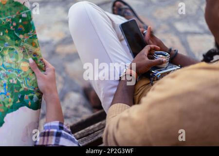 Ein Mann sitzt während einer Pause am Telefon. Seine Freundin sucht auf der Karte nach einem nächsten Reiseziel Stockfoto