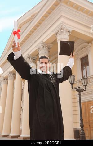 Glücklicher Student mit Abschluss nach der Abschlussfeier im Freien, Blick aus dem niedrigen Winkel Stockfoto