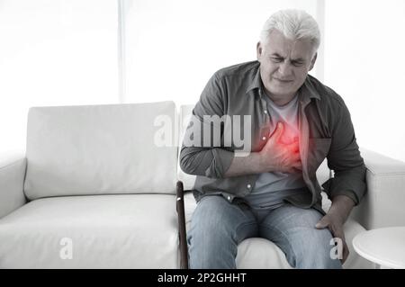 Älterer Mann mit Herzinfarkt auf dem Sofa Stockfoto